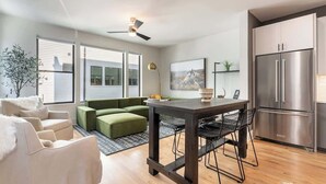 A modern kitchen with a large stainless steel refrigerator, a dining table with four chairs, and a green sofa in the living area. - The Bel- Vandy (Nashville)