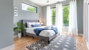 Une chambre moderne avec un lit, un ventilateur de plafond, une fenêtre avec des rideaux et une plante en pot.