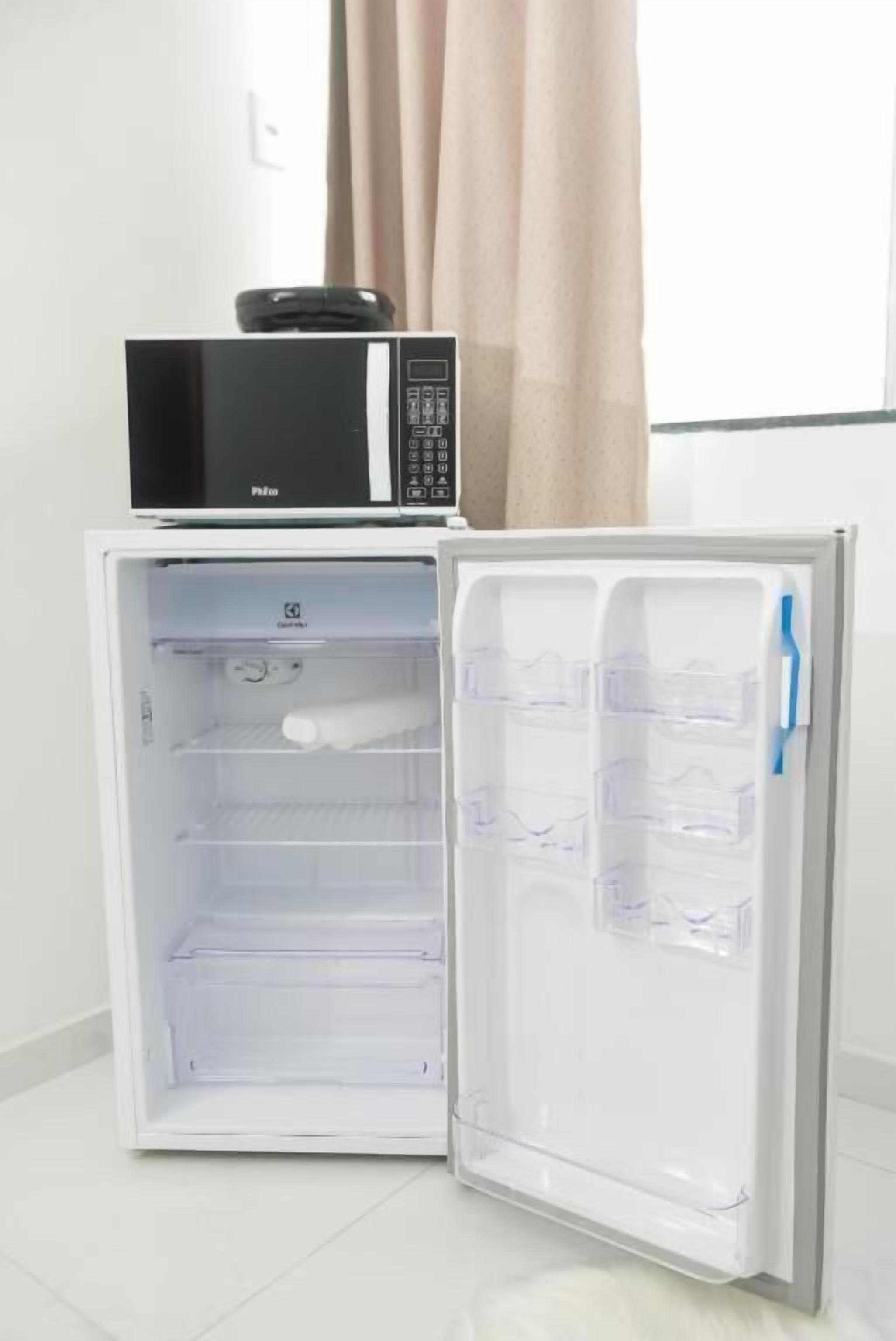 A compact refrigerator with a microwave on top, featuring multiple shelves and a freezer compartment.