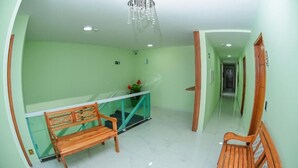 A hallway with a wooden bench, a glass railing, and a chandelier. - Pousada Central de Arraial (Arraial do Cabo)