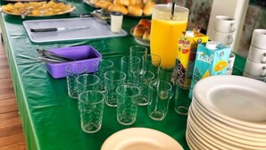 A breakfast buffet with various food items, glasses, and juice cartons. - Pousada Central de Arraial (Arraial do Cabo)