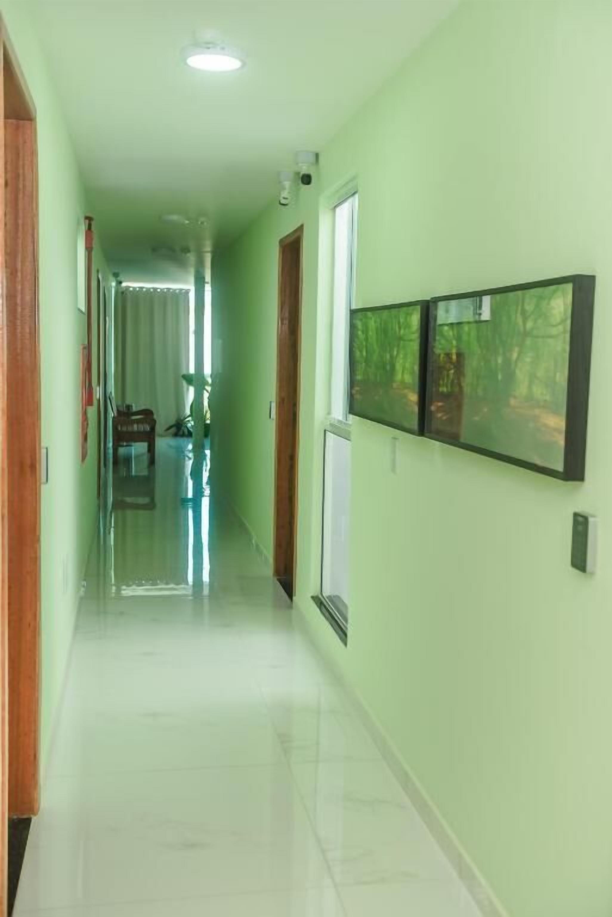 A hallway with a tiled floor, a wooden door, and a window with a view of trees.