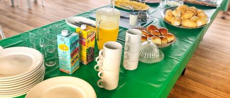 Un buffet de petit-déjeuner avec des assiettes, des tasses et divers aliments disposés sur une table verte.
