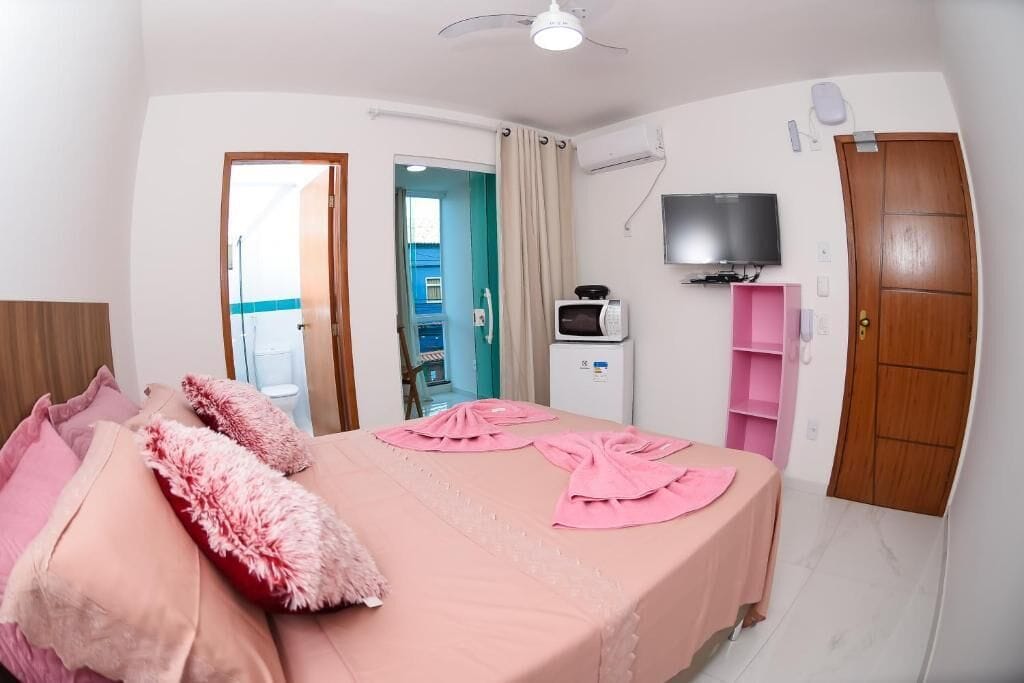 A bedroom with a bed, a TV, a microwave, and a wardrobe.