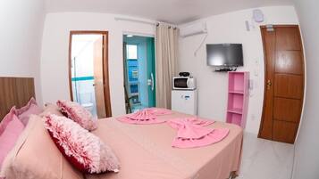 A bedroom with a bed, a TV, a microwave, and a wardrobe.