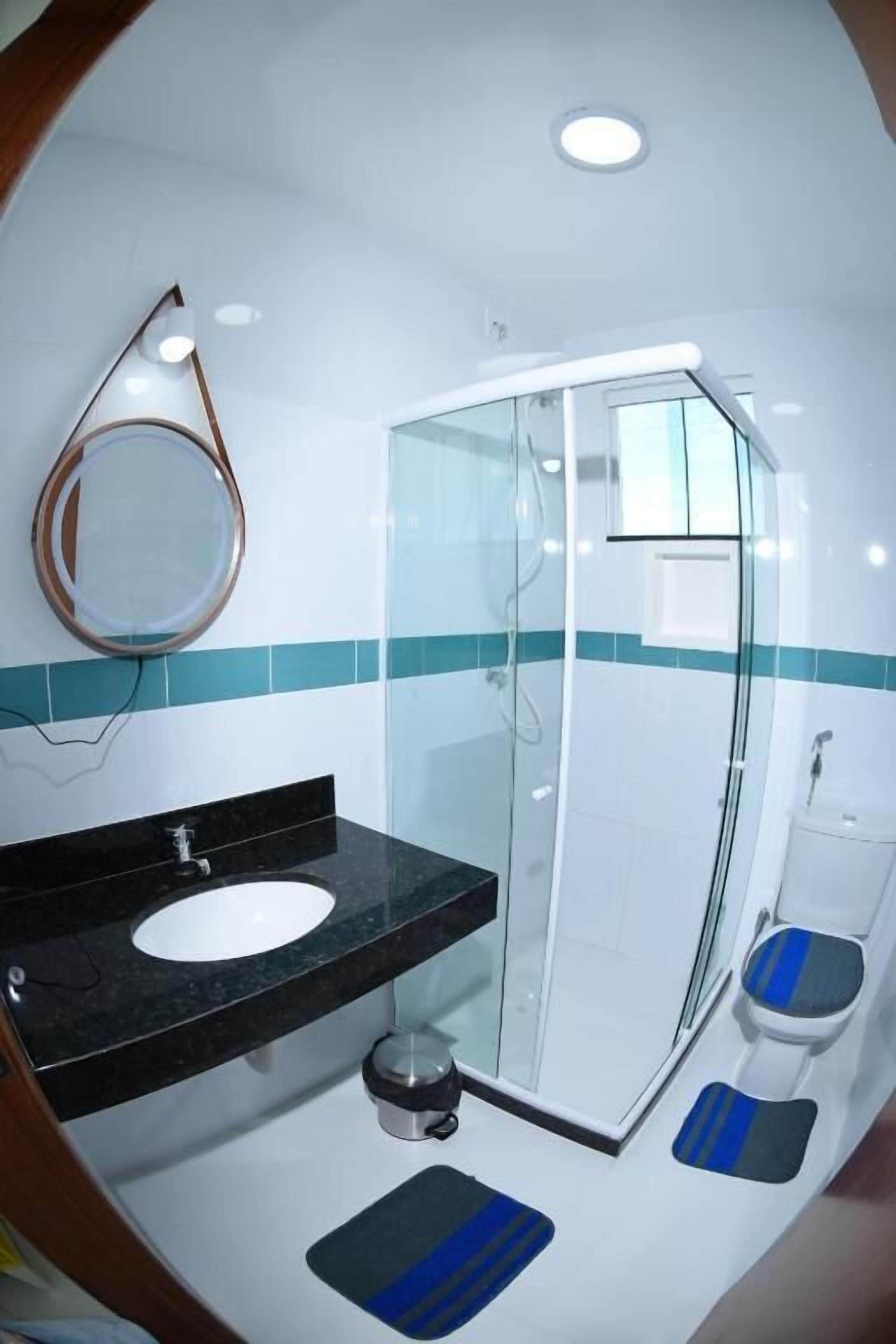 Un baño moderno con cabina de ducha de vidrio, lavamanos de encimera negro y un inodoro blanco.