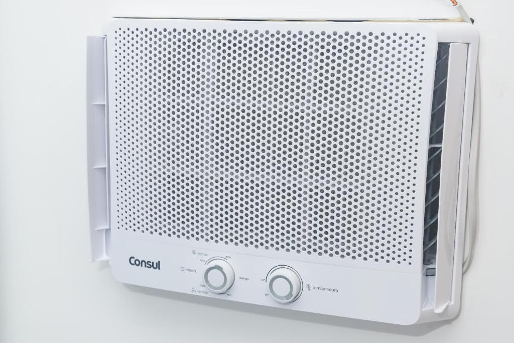 A white air conditioner unit with a perforated front panel and two control knobs labeled "Consul" and "temperatura".