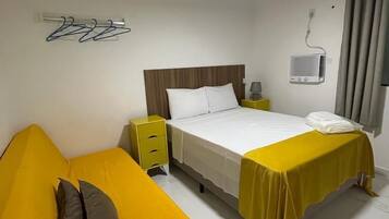 Habitació d'hotel amb llit, tauleta de nit, làmpada, televisió i un element decoratiu a la paret.