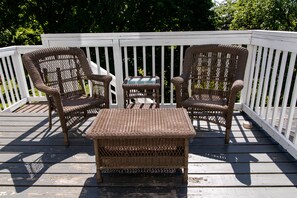 A deck with two wicker chairs and a small table.