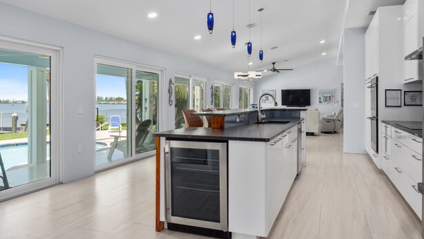 A modern kitchen with a central island, large windows, and a view of the outdoors. - 5BR/4.5B Beach House- heated pool, deep water dock, walk to beach! (Fort Pierce)