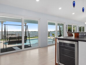 Relax in a spacious living area with a sliding glass door leading to a pool overlooking a body of water.