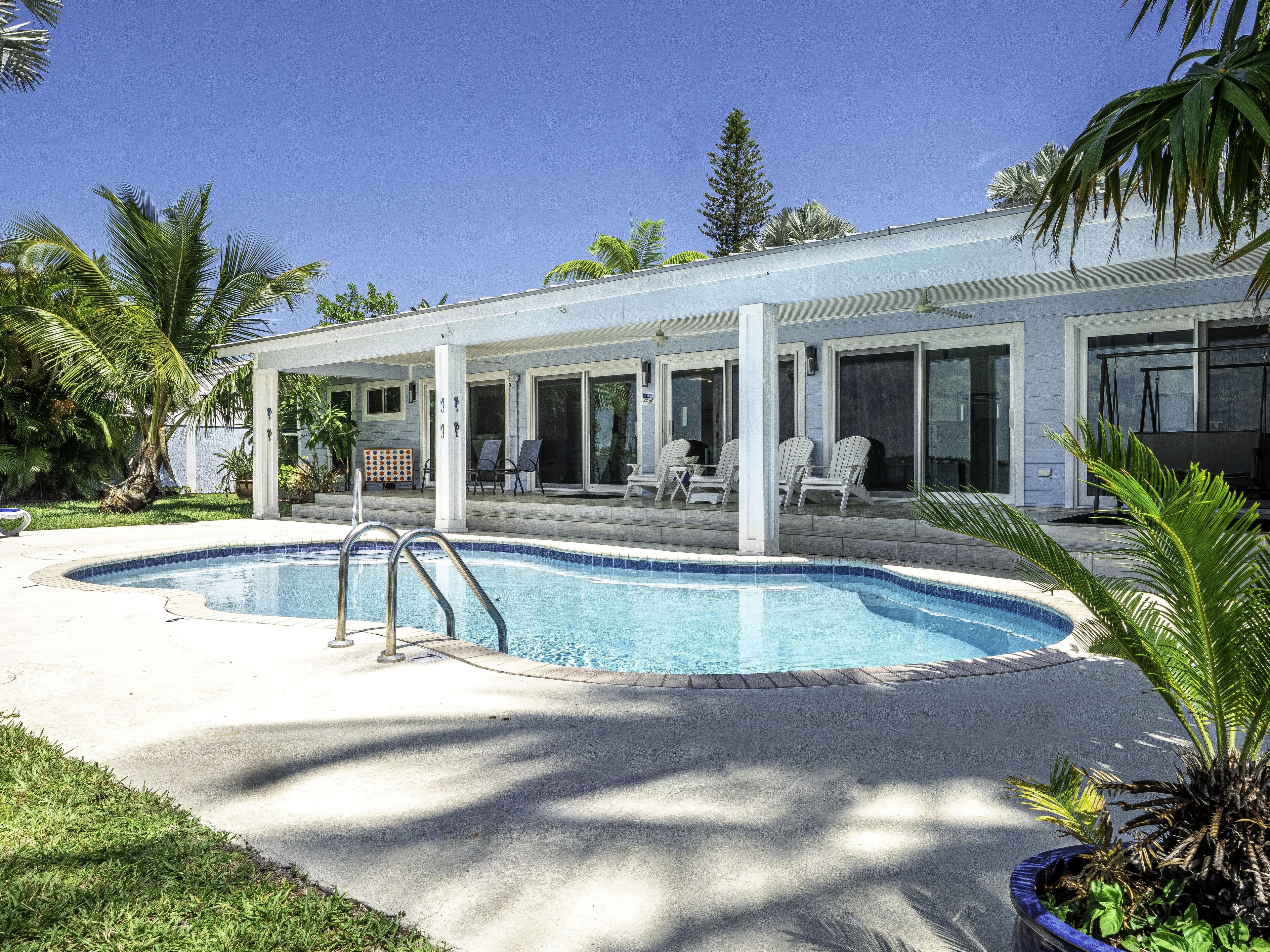 A modern house with a swimming pool, covered patio, and outdoor seating area.