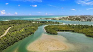 An aerial view of a coastal area with a large bay, a small island, and a distant cityscape. - 5BR/4.5B Beach House- heated pool, deep water dock, walk to beach! (Fort Pierce)