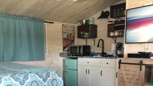 Une chambre confortable, aménagée comme un chalet, avec un lit, une kitchenette et un téléviseur.