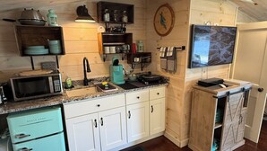 Une cuisine avec des meubles de rangement en bois, un four à micro-ondes, une cuisinière et un téléviseur.
