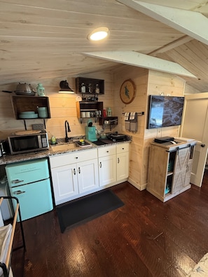 A kitchen with wooden cabinets, a microwave, a stove, and a television.