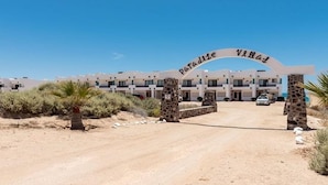 Un paysage désertique avec un grand bâtiment portant l’inscription « Paradise Villas » et une entrée dallée.