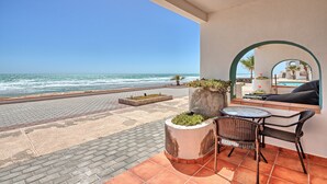 Un balcon avec vue sur l’océan, un coin salon avec une table et des chaises, et des plantes en pot.