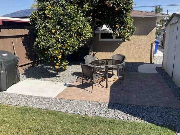 Enjoy al fresco dining on the patio surrounded by lush greenery and a barbecue grill.