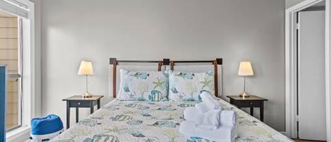 A neatly made bed with a floral bedspread, two bedside lamps, and a blue bean bag chair.