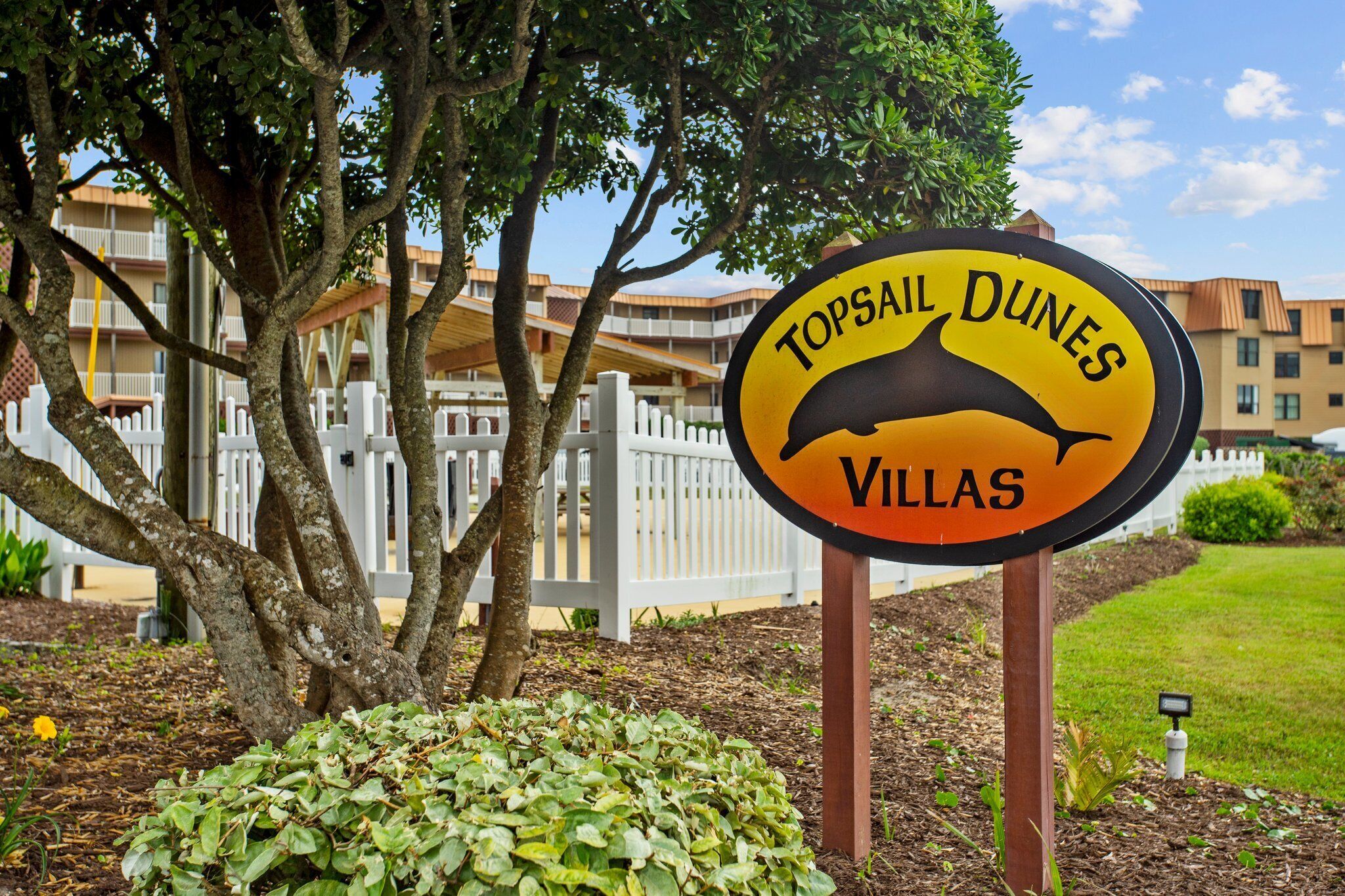 A sign for Topsail Dunes Villas with a dolphin graphic.