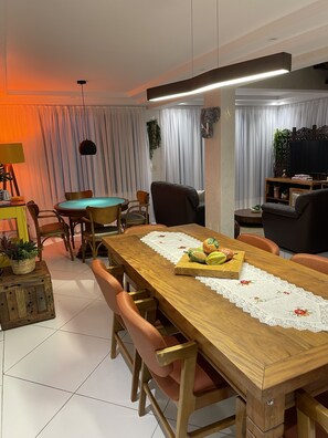 Un comedor con una mesa de madera, sillas y una mesa de billar verde.