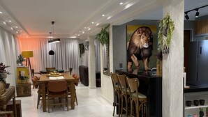 A modern living room with a dining area, a kitchen, and a large wall mural. - High standard, beachfront. (Ubatuba)