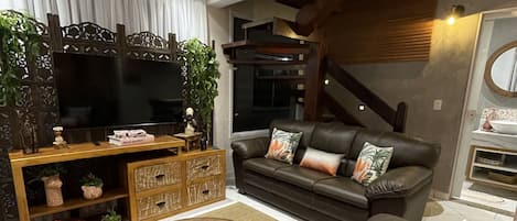 A modern living room with a brown leather sofa, a wooden coffee table, and a TV on a wooden stand.