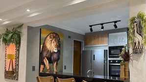 A modern kitchen with a central island, three wooden chairs, a refrigerator, and an oven. - High standard, beachfront. (Ubatuba)