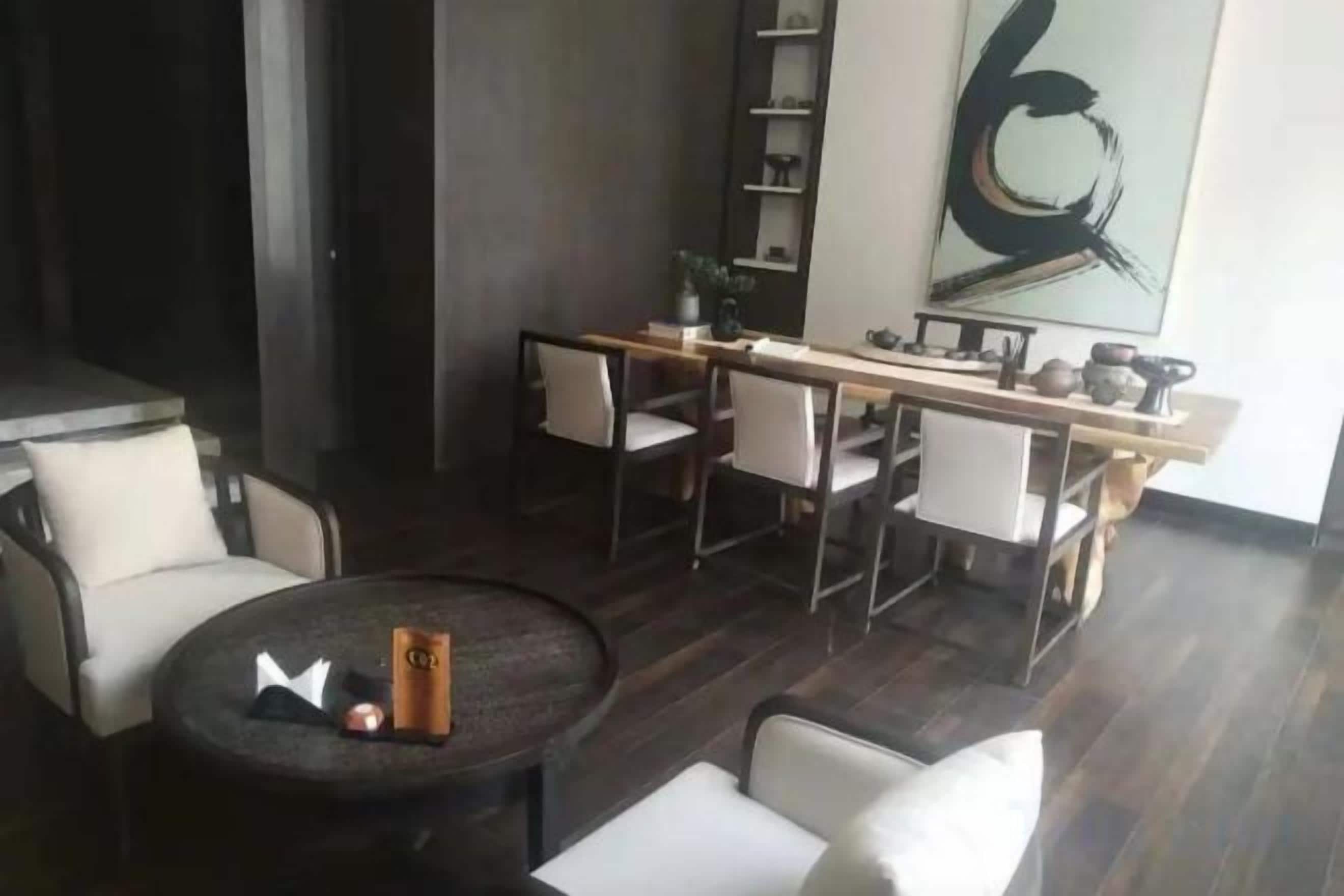 Un salon moderne avec une table basse ronde, un canapé et un coin repas comprenant des chaises et une longue table.