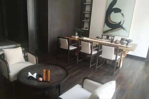 A modern living room with a round coffee table, a sofa, and a dining area with chairs and a long table.