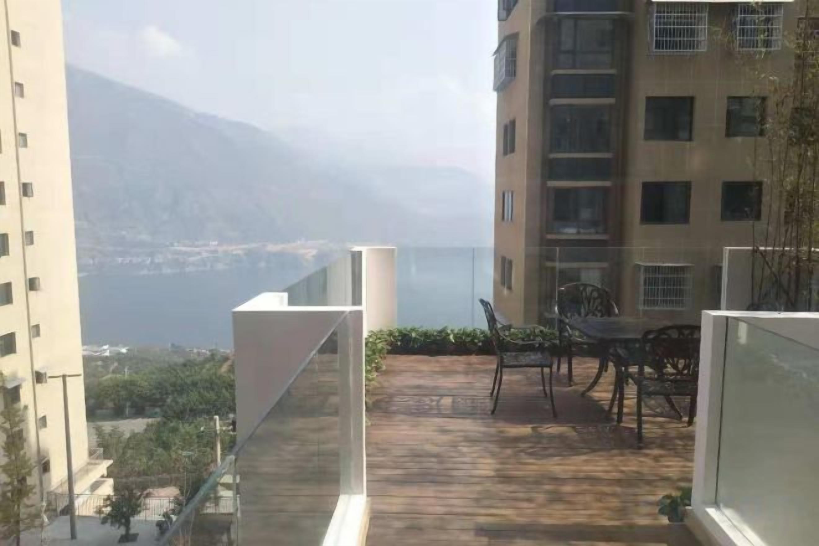 Un balcon avec vue sur un plan d’eau et des montagnes, aménagé avec une table et des chaises.