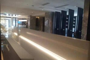 A modern hotel lobby with a long reception desk, marble columns, and a glass partition. - yueTing Chain Hotel (Hanyuan)
