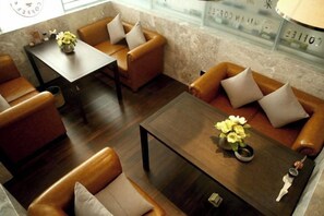 A hotel lobby with leather sofas, a wooden coffee table, and a vase of flowers. - yueTing Chain Hotel (Hanyuan)