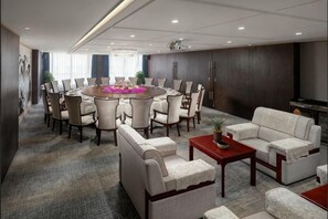 Une salle de conférence avec une table ronde entourée de chaises, d’un canapé et d’une petite table sur laquelle est posée une plante.