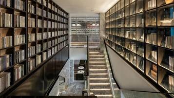 A library with bookshelves on both sides, a central staircase, and a marble floor.