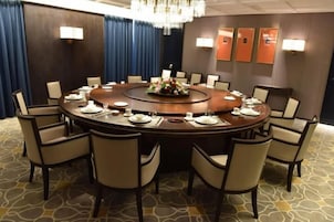 A conference room with a round table, chairs, and a floral centerpiece.