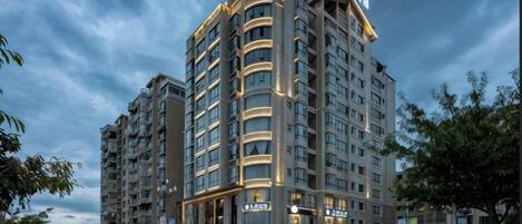Un hotel de varios pisos con un letrero llamativo en la parte superior, fachada bien iluminada y ubicación en esquina con vista a la calle.