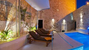 An indoor swimming pool with stone walls and lounge chairs. - Luxury Villa Old Story with Pool (Bol)
