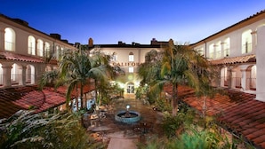 Ein Innenhof mit einem Brunnen, Palmen und einem Gebäude mit der Aufschrift 'CALIFORNIA'.