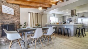 Eine moderne Küche mit Steinwand, Holzboden und einem Essbereich mit Tisch und Stühlen.