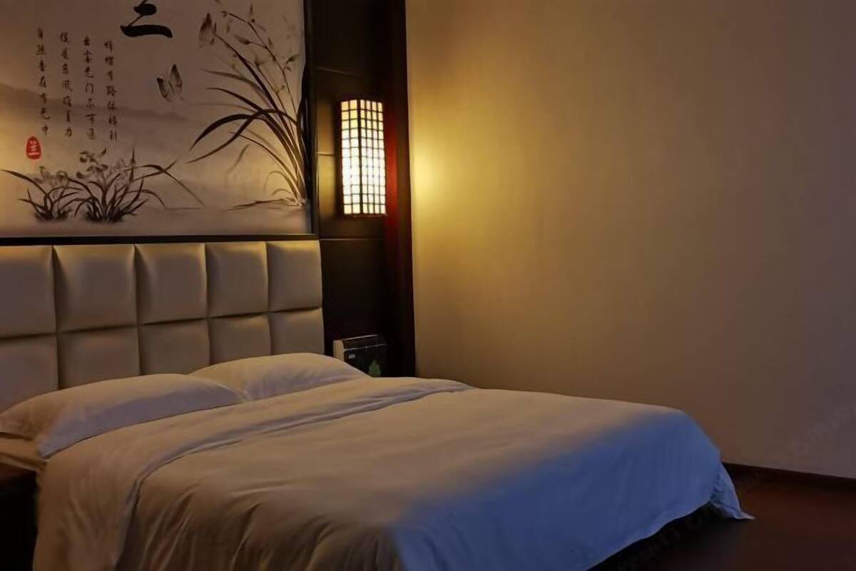 Una habitación de hotel con una cama, una obra de arte colgada en la pared y una lámpara de noche.