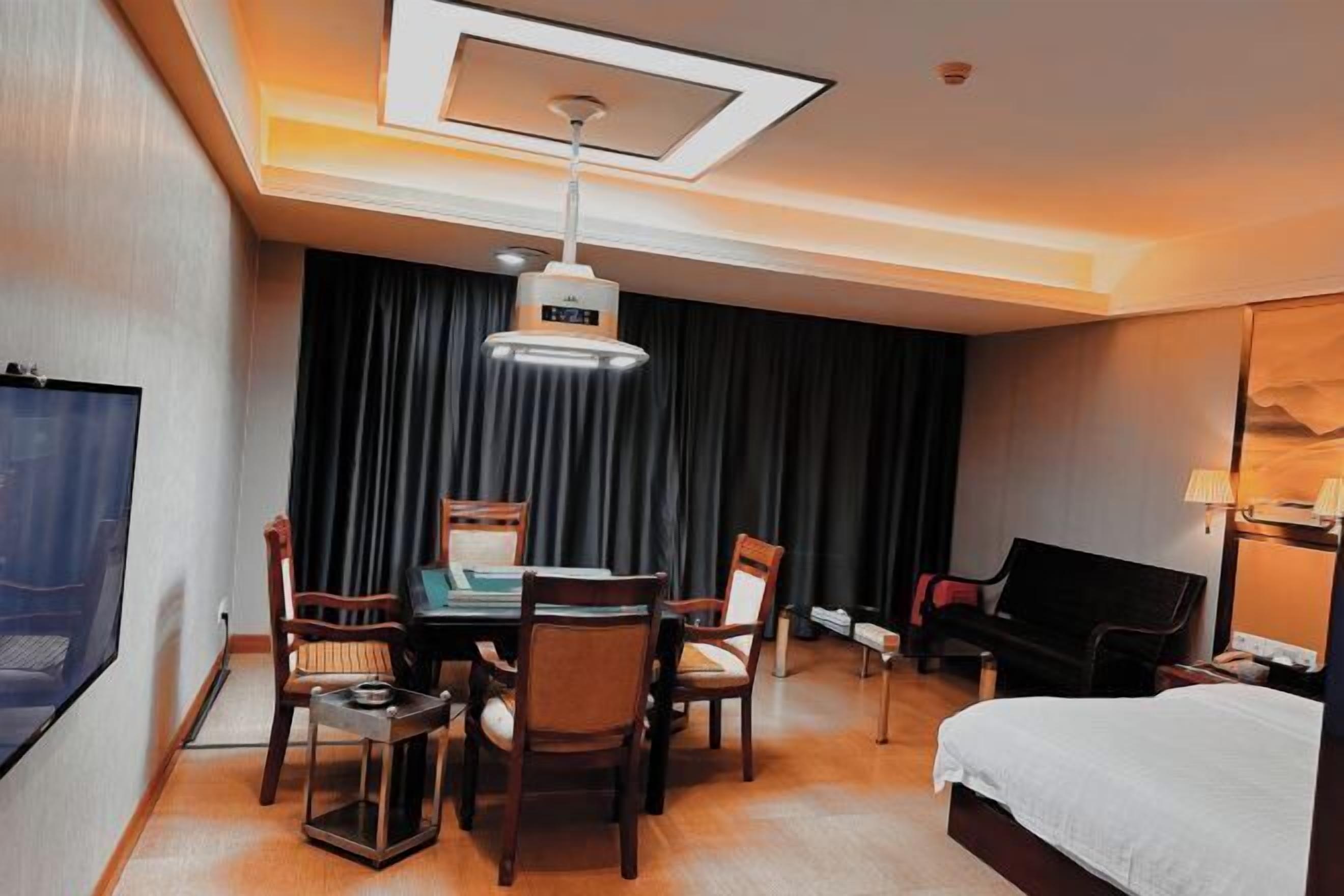 Habitación de hotel con cama, escritorio y silla, televisor y zona de comedor con sillas y mesa.
