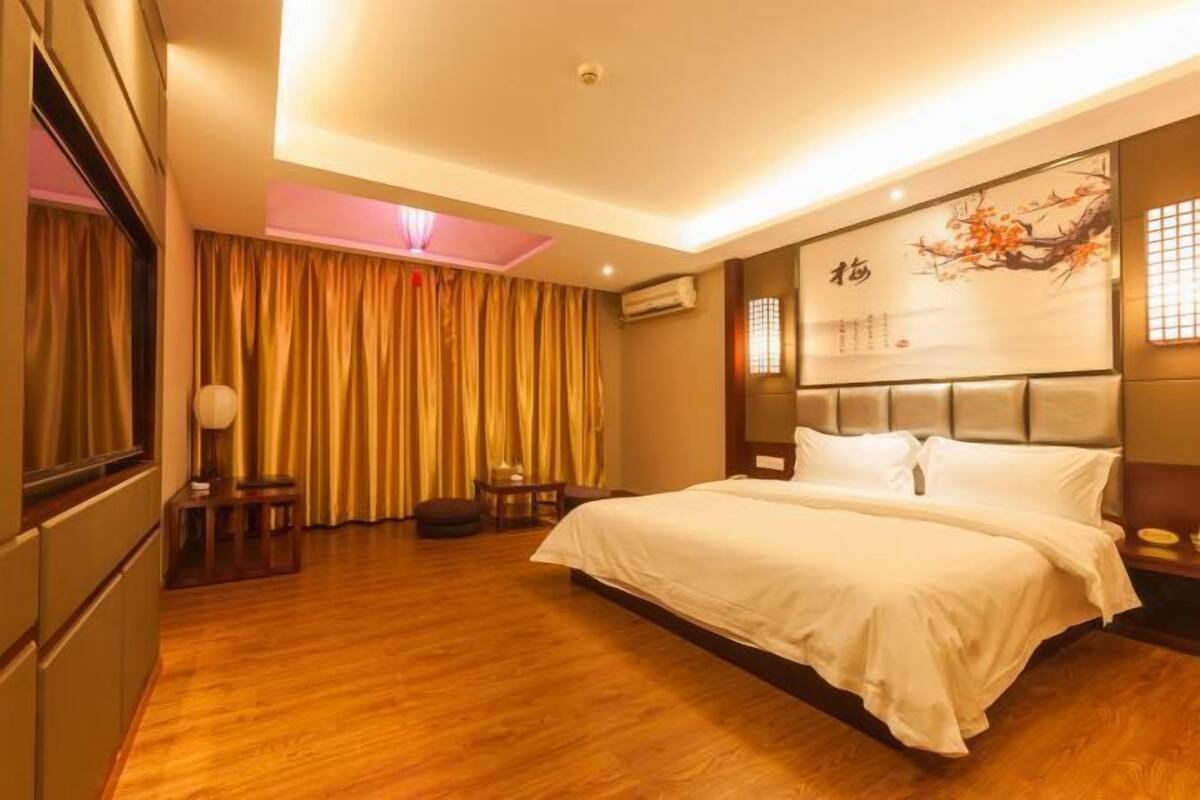 Habitación de hotel con una cama grande, un escritorio, una silla y una ventana con cortinas.