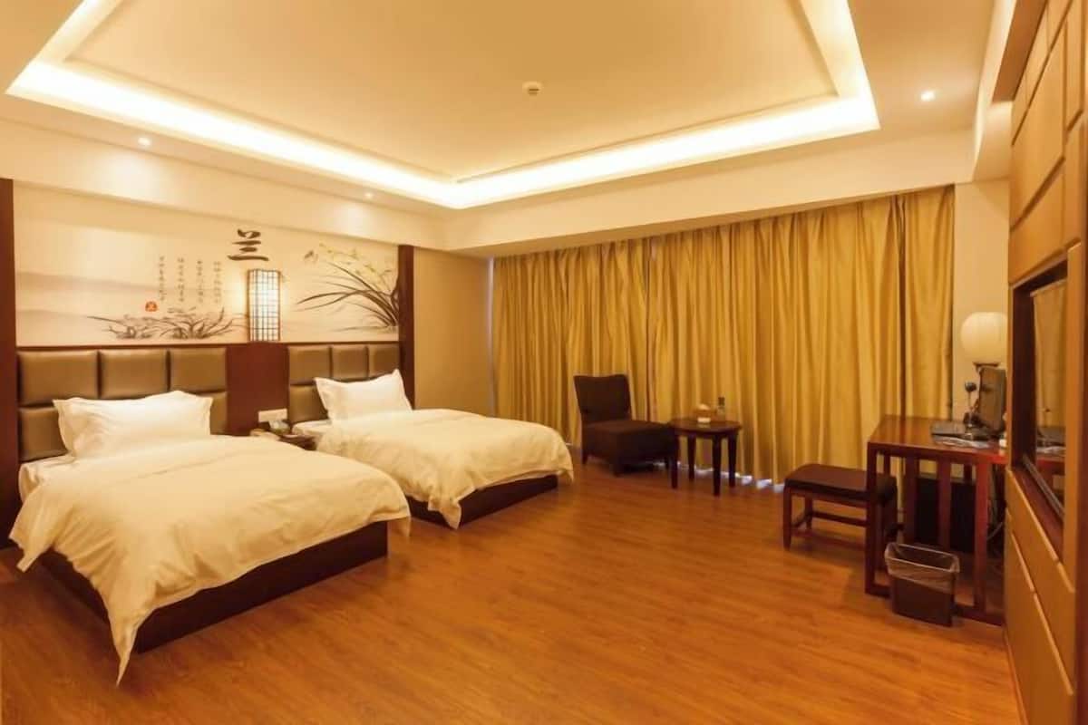 Habitación de hotel con dos camas, un escritorio, una silla y una cortina.