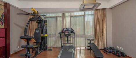 A home gym with a treadmill, weight bench, and exercise equipment.