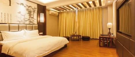 A hotel room with a large bed, a small table, a chair, and a decorative wall.