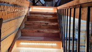 A wooden staircase with a metal railing, leading to a room with a table and a chair. - Beautiful Montana Cabin, at the base of the Pintler Mountains (Anaconda)