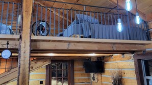 A wooden cabin interior with a loft bedroom, a fireplace, and a dining area. - Beautiful Montana Cabin, at the base of the Pintler Mountains (Anaconda)