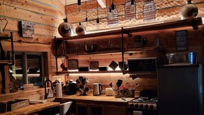 A rustic kitchen with wooden walls, a wooden countertop, hanging light fixtures, and a stove. - Beautiful Montana Cabin, at the base of the Pintler Mountains (Anaconda)